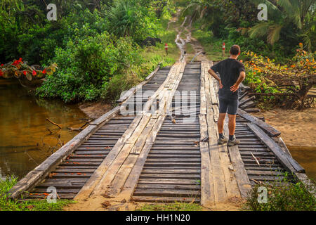 Mann, die Beurteilung der Schäden in die alte Holzbrücke im Norden Madagaskars Stockfoto