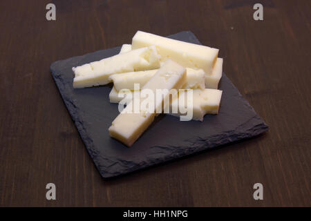 Käsestücke auf Schiefer Platte auf einem Holztisch Stockfoto