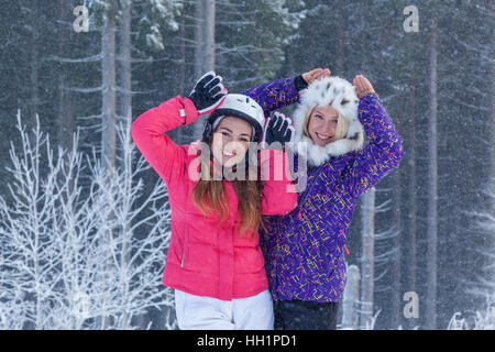 Bukovel 17. Dezember 2015 Mädchen Ukraine in Bukovel. Zwei attraktive junge Mädchen in hellen Anzügen posing gegen den Wald in Karpaten, Ukr Stockfoto