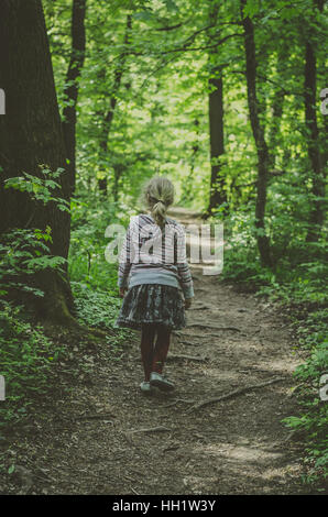kleines Mädchen im Pfad in dunklen grünen Wald wandern Stockfoto