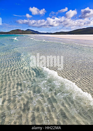 Whitehaven Beach auf Whitsunday Island von Coral Sea im Pazifik, Australien. Weißen Quarzsand unter frische und saubere Welle gegen Forstwirtschaft Hügel und blauer Himmel. Stockfoto