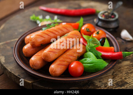 Gegrillte Würstchen und Gemüse auf einem hölzernen Hintergrund im rustikalen Stil. Stockfoto