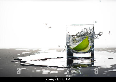 Limettenscheiben in ein Glas fallen gelassen Stockfoto