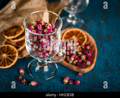 Trockenen Teerose Knospen in einem Glas auf dunkelblauem Hintergrund Stockfoto