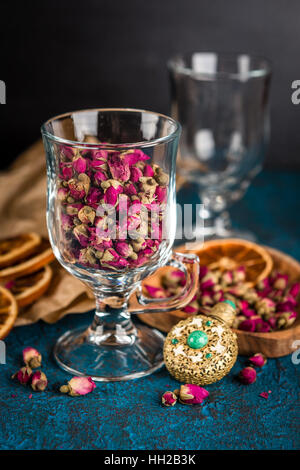 Trockenen Teerose Knospen in einem Glas auf dunkelblauem Hintergrund Stockfoto