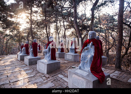 Stone Mönchs Statuen tragen Mäntel bei chinesischen Wald Stockfoto
