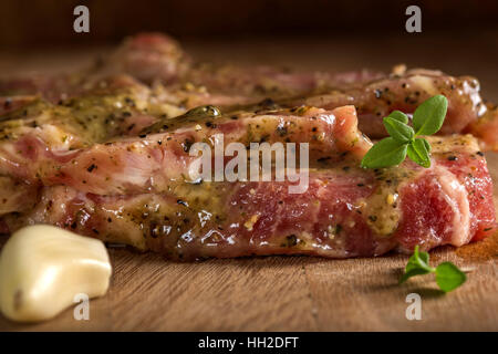 Marinierter Nacken Schweinefleisch mit Gewürzen bereit zum Grillen auf Holz Hintergrund Stockfoto