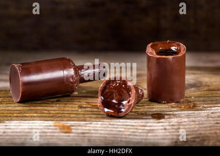 Praline in Form der Flasche gefüllt mit Likör Aromen über hölzerne Hintergrund Stockfoto