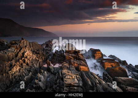 Letzte Sonnenstrahlen auf schroffen Felsen am Storms River, Südafrika Stockfoto