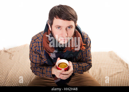 Porträt eines kranken Mannes mit Fieber in eine Decke gehüllt und halten einer Tasse warmen Tee Stockfoto
