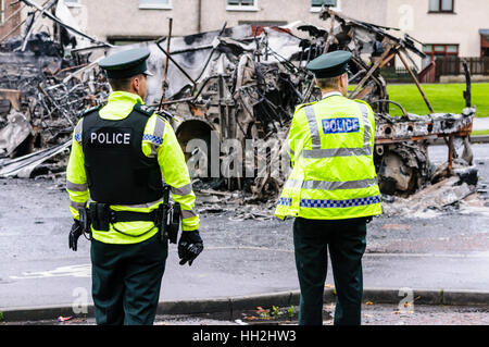 Zwei Polizisten am Unfallort Unruhen, wo ein Bus wurde entführt und ausgebrannt. Stockfoto