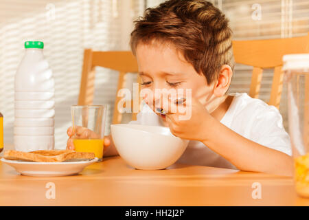 Fröhlicher Junge Getreide essen und trinken frische Saft Stockfoto