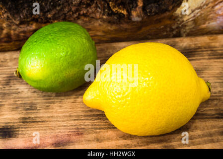 Scharf-saure Zitrone und Limone auf Holzbrett. Stockfoto