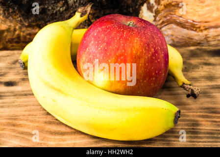 Geschmackvolle und reife Bananen und einen Apfel auf Holzbrett. Stockfoto