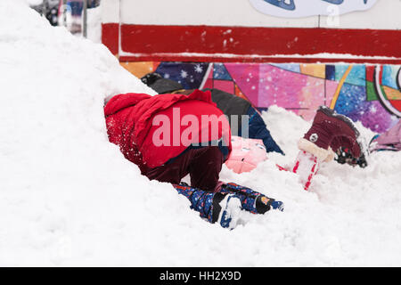 Moskau, Russland. Sonntag, 15. Januar 2017. Nicht erkennbare Kinder viel Spaß beim Graben von Löchern in einem Haufen von Neuschnee für weitere Entfernung von der Eisbahn auf dem Roten Platz gelagert. Nass, windig und verschneiten Sonntag in Moskau. Die Temperatur wird über-2C (28F). Schwere Wolken, Schneeschauer. Straßenreinigung und Schnee, die Reinigung von Fahrzeugen beschäftigen. © Alex Bilder/Alamy Live-Nachrichten Stockfoto