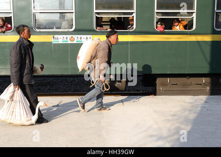 (170117) - CHENGDU, 17. Januar 2017 (Xinhua)--zwei Passagiere aussteigen dem 5633 grüne Zug auf dem Sichuan-Teil des Südwest-China Chengdu-Kunming Eisenbahn Haltestelle Wiederverwertung und Kopf zu einer lokalen Farm zu vermarkten, 16. Januar 2017. Da moderne Hochgeschwindigkeitszüge vorbei neue Stationen in ganz China gedreht, durchläuft ein langsamen grüner Zug noch Teilbereichen Armut Daljan Berge, wo die Menschen von Yi ethnische Gruppe hauptsächlich Leben. Altmodische Zug begann 1970 mit keine Klimaanlage und Speisewagen. Jetzt ist es noch eine preiswerte und Convinient Weise für die lokale Bevölkerung zu reisen. ( Stockfoto