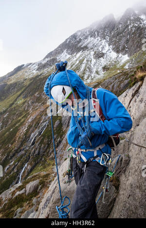Ein Bergsteiger Aufwickeln Kletterseil um seinen Körper vorbereitet, eine Rock-Gerangel in Cwm Idwal, Ogwen, Snowdonia, North Wales, UK, Großbritannien zu führen. Stockfoto