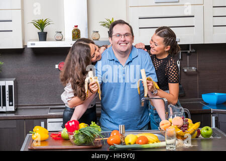 Zwei junge Frauen werden Bananen Midle Alter Mann gefüttert. Stockfoto