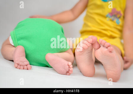 Kleines Mädchen ist ihr Baby Bruder trösten. Schwarz / weiß Foto mit soft-Fokus auf ihren Füßen. Stockfoto