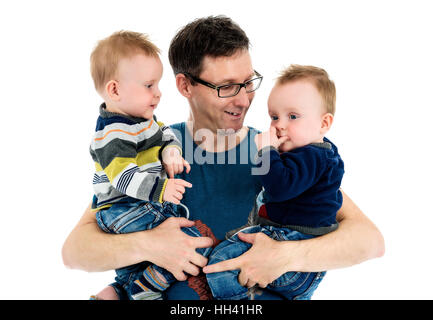 Stolzer Vater hält seine Zwillingssöhne in seinen Armen. Eine alleinerziehende Mutter ist seine Zwillinge tragen und lächelnd. Isoliert auf weißem Hintergrund. Stockfoto