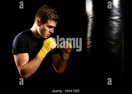 Attraktive junger Mann in der gelben Box Packungen ist Training und Boxsack schlagen. Fitness, aerobic-Übungen für aktive Menschen. Starker Athlet isoliert auf Stockfoto