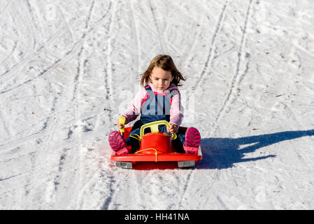 Kleines Mädchen schieben mit Bob im Schnee im Winter. Winterurlaub in den Bergen mit Glück-Konzept. Kinder Outdoor-sport Aktivität. Stockfoto