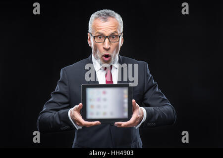 Überrascht reifer Geschäftsmann hält digital-Tablette und Blick in die Kamera Stockfoto