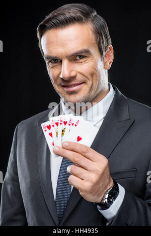 Lächelnd Mann zeigt Spielkarten mit royal Straight flush Stockfoto