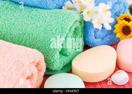 Bunte gerollte Handtücher mit Blumen, Seifen und Steinen Nahaufnahme Bild. Stockfoto