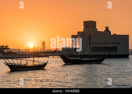 Blick auf den Sonnenuntergang über traditionelle Dhaus Boote mit Museum für islamische Kunst hinter, Doha, Katar