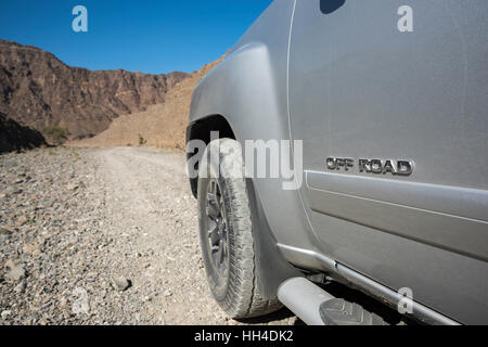 4 x 4 in der Wüste von Steinen (Nahaufnahme von vorne links) mit dem Text "OFF ROAD" an der Tür des Fahrzeugs geschrieben Stockfoto