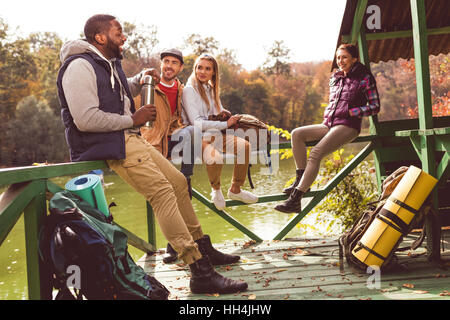 Gruppe von jungen Freunden Reisende ruht in der Nähe von ruhiger Fluss im herbstlichen Wald Stockfoto