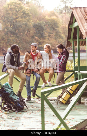 Gruppe von jungen Freunden Reisende ruht in der Nähe von ruhiger Fluss im herbstlichen Wald Stockfoto