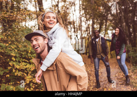 Gruppe der jungen happy Friends huckepack und Spaß im herbstlichen Wald Stockfoto