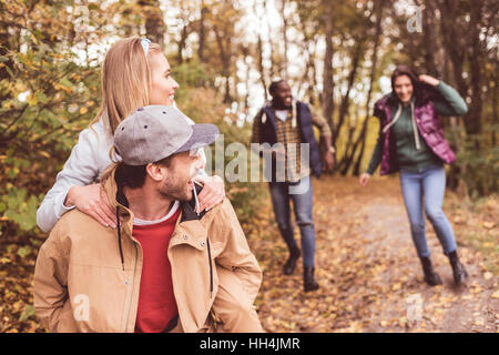 Gruppe der jungen happy Friends huckepack und Spaß im herbstlichen Wald Stockfoto