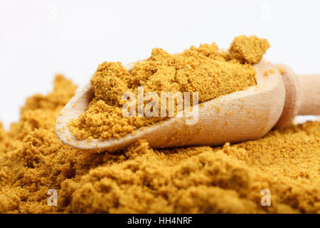 Aromatische gelbe Farbe Currypulver Zutat auf weißen Tisch mit hölzernen Schaufel und rotem Stofftasche im Hintergrund Stockfoto