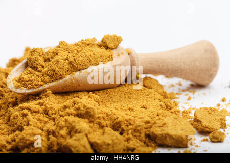 Aromatische gelbe Farbe Currypulver Zutat auf weißen Tisch mit hölzernen Schaufel und rotem Stofftasche im Hintergrund Stockfoto