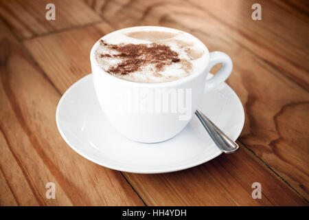 Cappuccino. Tasse Kaffee mit Milchschaum und Zimt steht auf Holztisch Stockfoto