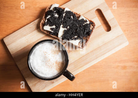 Tasse Cappuccino und ein Sandwich mit schwarzem Kaviar stehen auf Holztisch, Draufsicht, selektiven Fokus Stockfoto