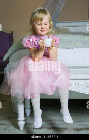 Glückliche Prinzessin Mädchen im rosa Kleid und Krone in ihrem königlichen Zimmer posiert und lächelnd. Stockfoto