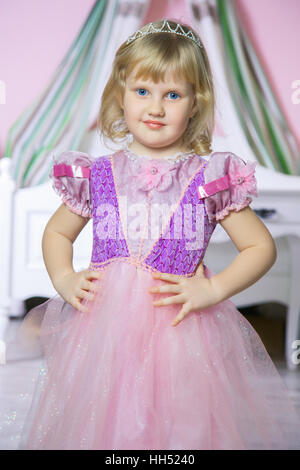 Glückliche Prinzessin Mädchen im rosa Kleid und Krone in ihrem königlichen Zimmer posiert und lächelnd. Stockfoto