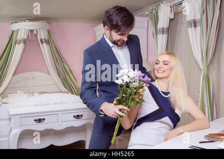 Schönen jungen Mann überraschend schöne Freundin und gibt ihren Blumenstrauß lila weiß. Stockfoto