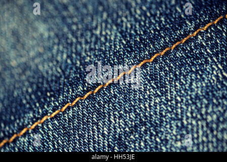 Makro Nahaufnahme gelbe Naht auf einem Paar von verblassten Jeans. Der Faden auf das Material in einer diagonalen schräge. Stockfoto