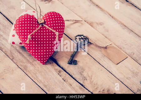Herz Stoff und Vintage Schlüssel mit Tag auf Holztisch Hintergrund. Stockfoto