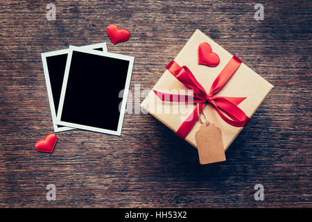 Leere Foto Frame und Geschenk-Box mit roten Herz auf Holz Hintergrund. Stockfoto