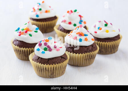 Hausgemachte Schokolade Cupcakes mit weißem Zuckerguss auf weißem Holz Hintergrund Stockfoto