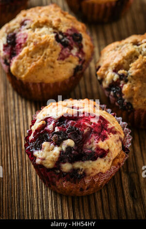 Hausgemachte schwarze Beeren-Muffins. Muffins mit schwarzer Johannisbeere für gesundes Frühstück am rustikalen Holztisch Stockfoto
