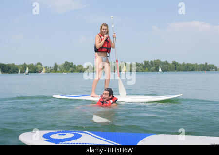 Frau am Paddel Board, Mann im Wasser Stockfoto