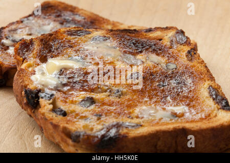 Nahaufnahme von zwei Scheiben geröstetes Johannisbeere Brot mit Schmelzen von Butter auf einem Holzbrett, erschossen in natürlichem Licht mit flachen DoF Stockfoto