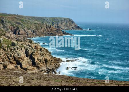 Wellen brechen sich an der felsigen kornischen Küste in der Nähe des Dorfes Porthgwarra. Stockfoto